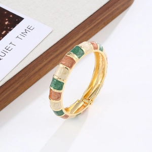 Detail of bohemian gold-plated enamel hinge bracelet with vintage green and orange textures