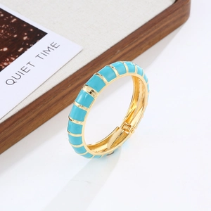 Detail of bohemian gold-plated enamel bangle featuring a teal bamboo-style texture and hinge