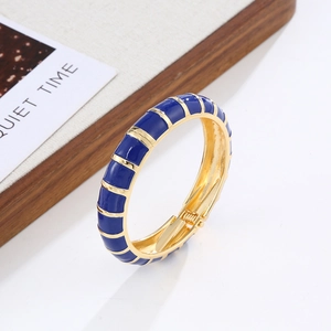 Detail of blue enamel inlay on golden bohemian bangle featuring a spring hinge closure