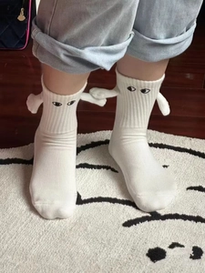 Gros plan de chaussettes blanches magnétiques amusantes qui se tiennent la main