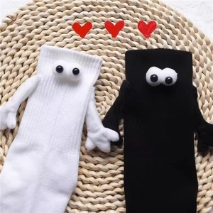 Détail de chaussettes magnétiques se tenant la main avec yeux 3D sur tapis