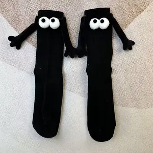 Détail de chaussettes mi-mollet noires avec yeux cartoon 3D et petites mains aimantées