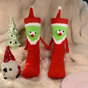 Détail de chaussettes de Noël rouges avec yeux 3D et mains aimantées sur tapis doux