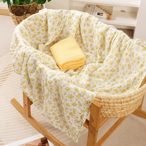 Soft muslin cotton baby swaddle set with lemon print and yellow wrap in a cradle