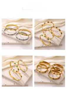 Detail of geometric titanium steel bangles with colorful stones on beige silk fabric