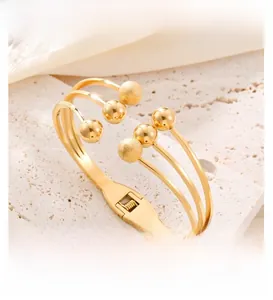 Detail of gold multi-layer open bangle with polished and frosted spherical beads on stone