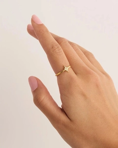 Close-up of a delicate gold-toned star ring with small crystals on a person's finger