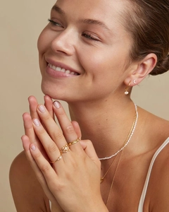 Close-up of golden star-pattern rings and layered pearl necklaces on a female model