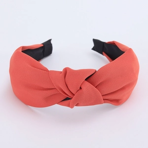 Macro detail of the coral red fabric headband featuring a top knot and twill texture