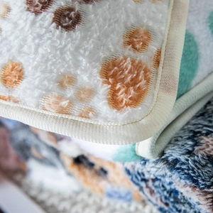 Soft coral fleece pet blanket with colorful paw prints and reinforced stitched edges