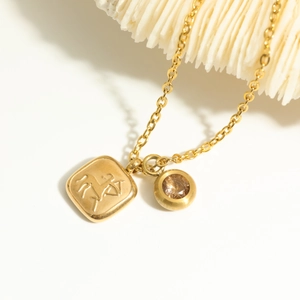 Detailed close-up of 18K gold zodiac horse pendant and champagne birthstone on a necklace