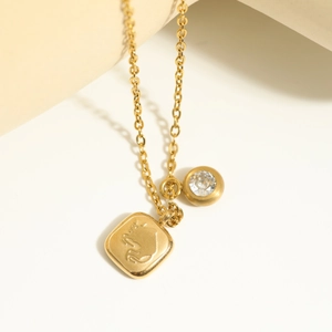 Close-up of gold 18K plated stainless steel necklace with relief pendant and round zircon