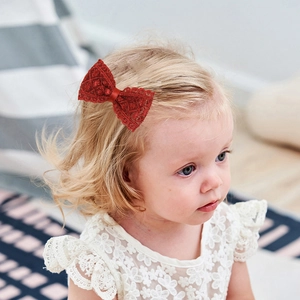 Fillette portant une barrette nœud en dentelle rouge pour une coiffure de princesse