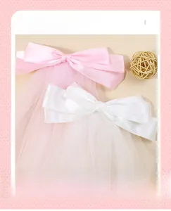 Détail de grandes barrettes à nœuds en tulle rose et blanc avec rubans double épaisseur