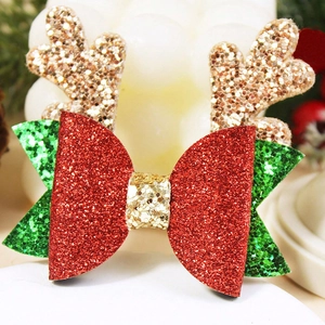 Détail d'une pince à cheveux de Noël avec nœuds pailletés rouge vert et bois de renne dorés