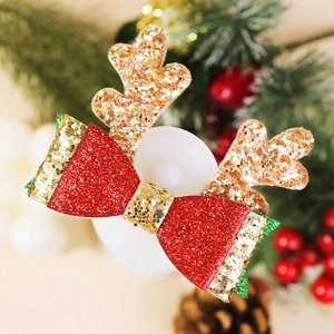 Détail de la pince de Noël à paillettes avec bois de renne et nœud rouge et doré festif