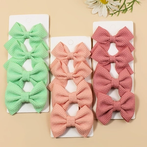 Set of 12 waffle texture bow hair clips in mint, orange, and rose pink on display card