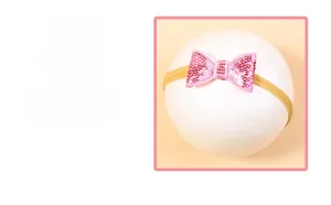 Détail d'un bandeau à nœud en paillettes roses pour bébés sur un fond beige doux