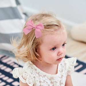 Pink waffle texture bow hair clip worn by a toddler girl for a cute styling accessory