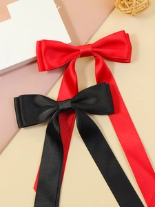 Close-up of elegant black and red satin bow hair clips with long flowing ribbons