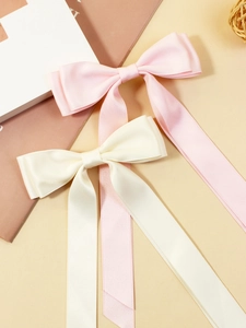 Detail of pink and beige satin bow hair clips with long elegant ribbon streamers