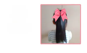 Detailed back view of a pink long ribbon bow hairband on a young girl hairstyle