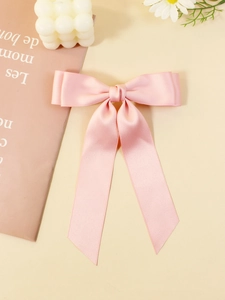 Dettaglio di un fiocco di raso rosa con lunghi nastri su uno sfondo decorativo