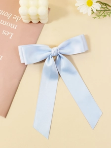 Dettaglio del fiocco per capelli in raso azzurro con nastri lunghi su sfondo decorativo