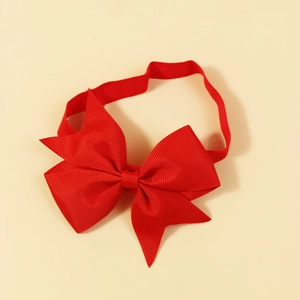 Red grosgrain bow elastic headband for babies on warm beige background in top view