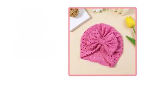 Detail of pink baby headband featuring large bow and breathable eyelet embroidery texture