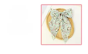 Detail of floral bow hair clip with mint green fabric and long ribbons for daily wear