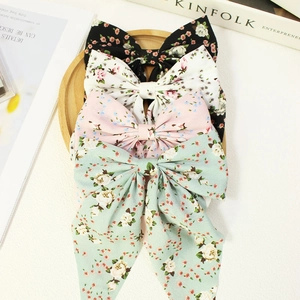 Floral print ribbon bow hair clips in black, pink, white, and mint green on wooden tray