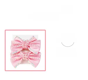 Détail de barrettes à nœuds en satin rose avec cristaux brillants sur carte support