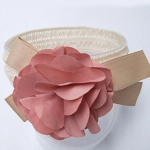 Macro view of pink fabric flower and champagne ribbon detail on baby lace headband
