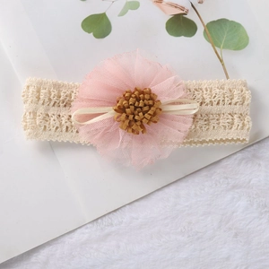 Detail of pink mesh flower and beige lace headband on a soft plush background