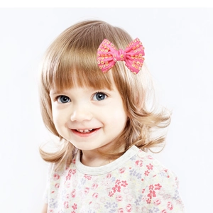 Pink handmade mesh hair bow with shiny gold sequins for children worn by a model