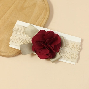 Detail of baby lace headband with deep red fabric flower on cream cardboard display