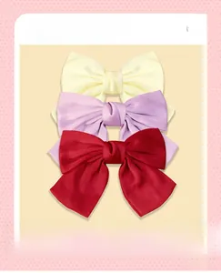 Dettaglio dei fermagli per capelli a fiocco in raso in beige, lavanda e rosso intenso
