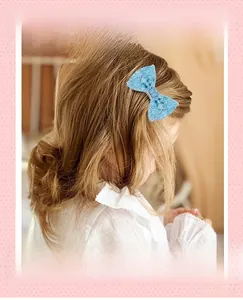 Blue sequin bow hair clip with pearls worn by a little girl for a daily cute hairstyle
