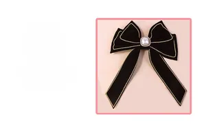 Close-up of black velvet bow hair clip with pearl centerpiece and gold bead trim details
