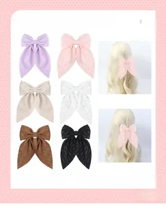 Detail showing various colors of rhinestone bow hair clips on a pink patterned background