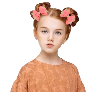 Paire de nœuds roses pour cheveux avec bords dorés brillants portés par enfant