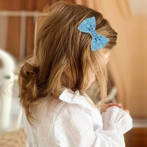 Blue rhinestone bow hair clip for girls shown on model with a cute minimalist design
