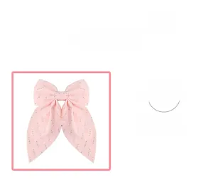 Detail showing pink rhinestone bow hair clip with soft fabric texture and sweet design