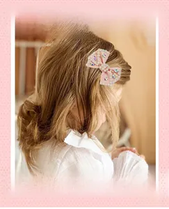 Detailed close-up of a pink ribbon bow hair clip with colorful rhinestones and star accents