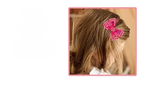 Gros plan sur un nœud papillon pour cheveux rose rouge avec des strass brillants