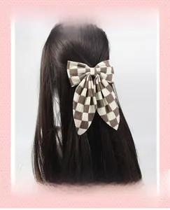 Détail d'une barrette à nœud à carreaux marron montrant le tissu velours sur cheveux longs