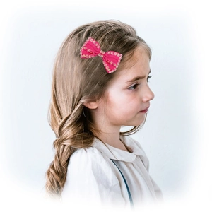 Pink handmade bow hair clip with bead edge on girl side view in white background