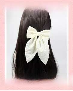 Detail view of a cream white jacquard bow hair clip with elegant long ribbon streamers