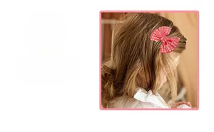 Detailed view of children's pink bow hair clip with gold rhinestone beads on hair